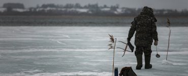 man ice fishing on a lake