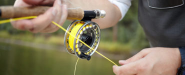 fly reel in a fishmans hand