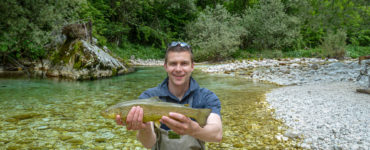 a fisherman holding a rare marble trout