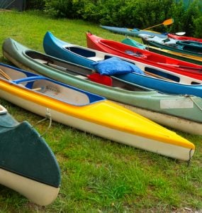 canoes and kayaks lined up on the ground