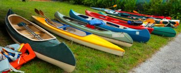 canoes and kayaks lined up on the ground