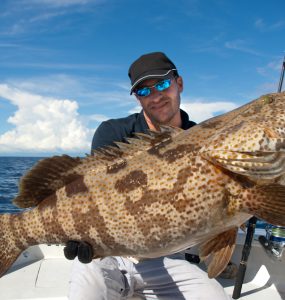 lucky fisherman holding a big grouper