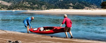 two seniors carrying a kayak