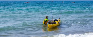 person with a fishing kayak on the beach