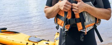 man putting on a life jacket to go kayak fishing