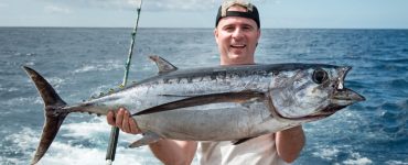 man holding a tuna caught on a rod and reel