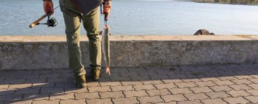 man wearing fishing pants holding a fish